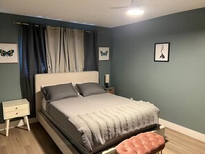 A bedroom with a bed, a nightstand, a bedside table, a pink ottoman, and two wall-mounted pictures. - 4-bedroom Pool house in serene Hollywood with cool AC breeze (Hollywood)