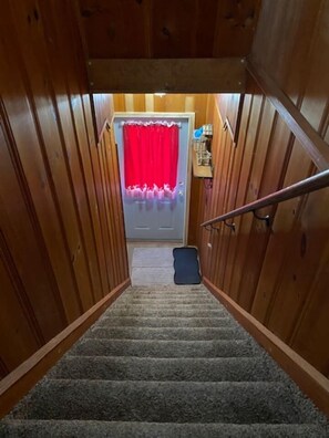 Un intérieur en bois avec un escalier recouvert de moquette menant à une porte ornée d  ’un rideau rouge.