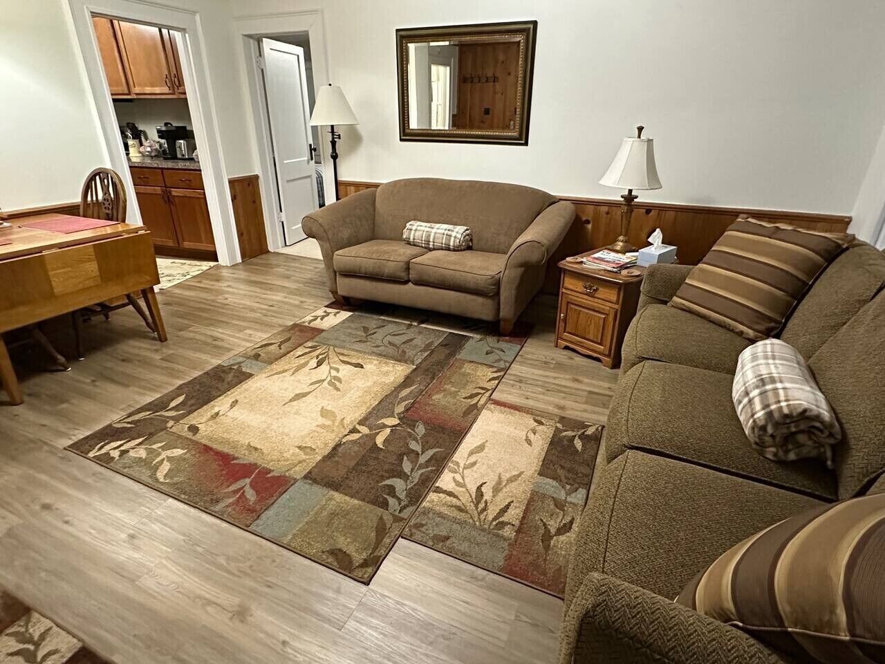 Un salon comprenant un canapé, une table basse, un tapis et un coin repas avec une table et des chaises.