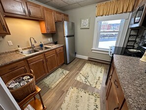 Una cocina con armarios de madera, refrigerador de acero inoxidable, encimeras de granito y una ventana con vistas.
