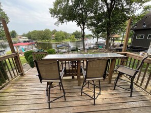 Eine Holzterrasse mit Tisch und Stühlen mit Blick auf einen See und Boote.