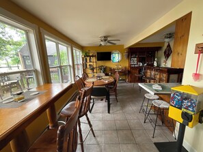 Zona pranzo con tavolo e sedie in legno, un bancone bar e una finestra con vista sull'esterno.