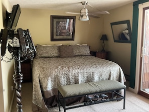 A bedroom with a bed, a bench, a ceiling fan, a framed picture, and a lamp. - Unique 3+bedroom house at the beautiful Lake of Egypt (Marion)
