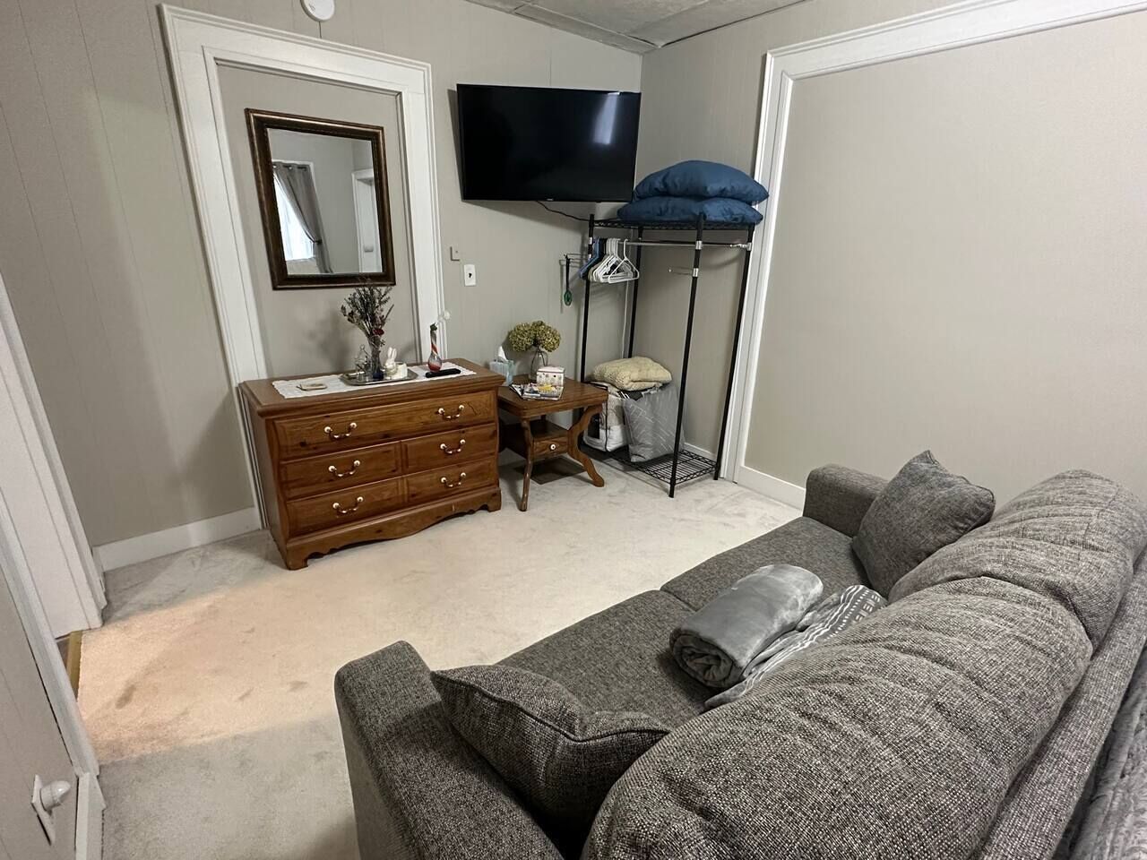 Un espace de vie compact comprenant un canapé, une commode, un téléviseur et une petite table sur laquelle est posé un vase.