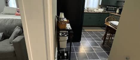A kitchen with dark tiled flooring, a refrigerator, and a microwave.