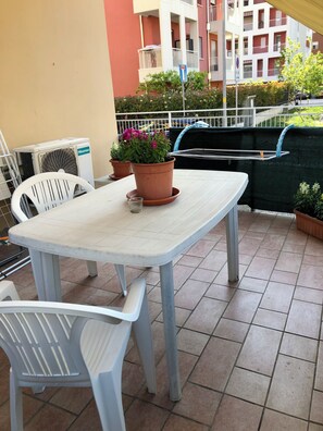 A patio with a table and chairs, potted plants, and an air conditioning unit. - Vrbo Property (Verona)
