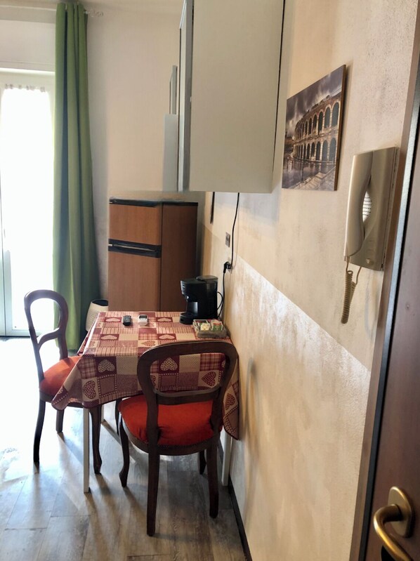 A small dining area with a table set for two, a coffee maker, and a wall-mounted phone. - Vrbo Property (Verona)