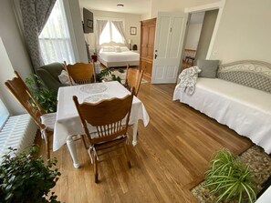 A room with a dining table, chairs, a sofa, and a bed.