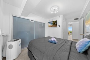 A bedroom with a bed, a wall-mounted TV, a sliding door closet, and a ceiling light. - Miami Beachfront Oasis with Stunning Ocean Views (Miami Beach)