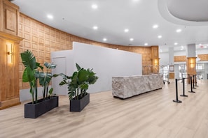 A reception area with a wooden panel wall, a marble reception desk, and potted plants. - Miami Beachfront Oasis with Stunning Ocean Views (Miami Beach)