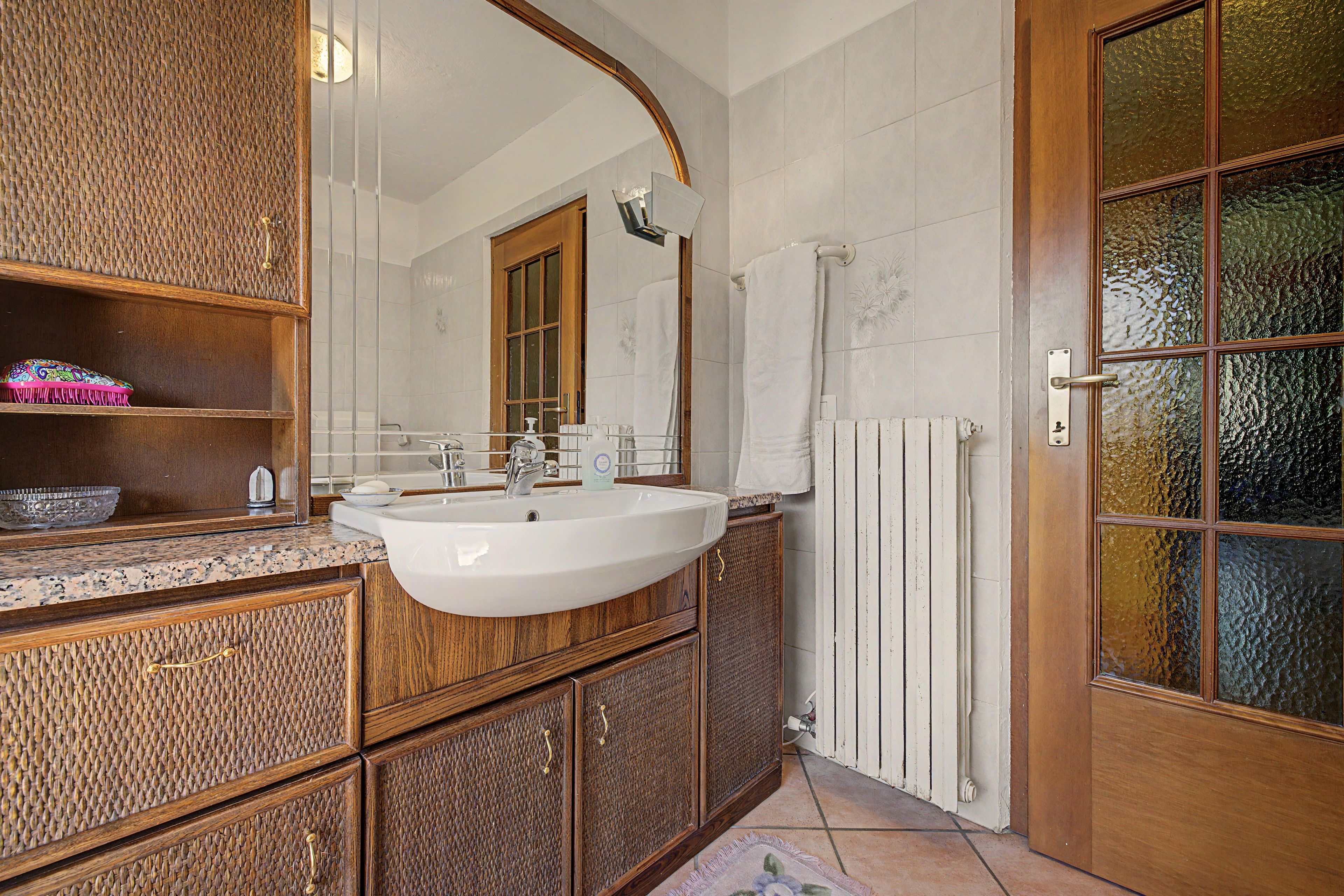 A bathroom with a wooden vanity, a white sink, and a glass shower enclosure.