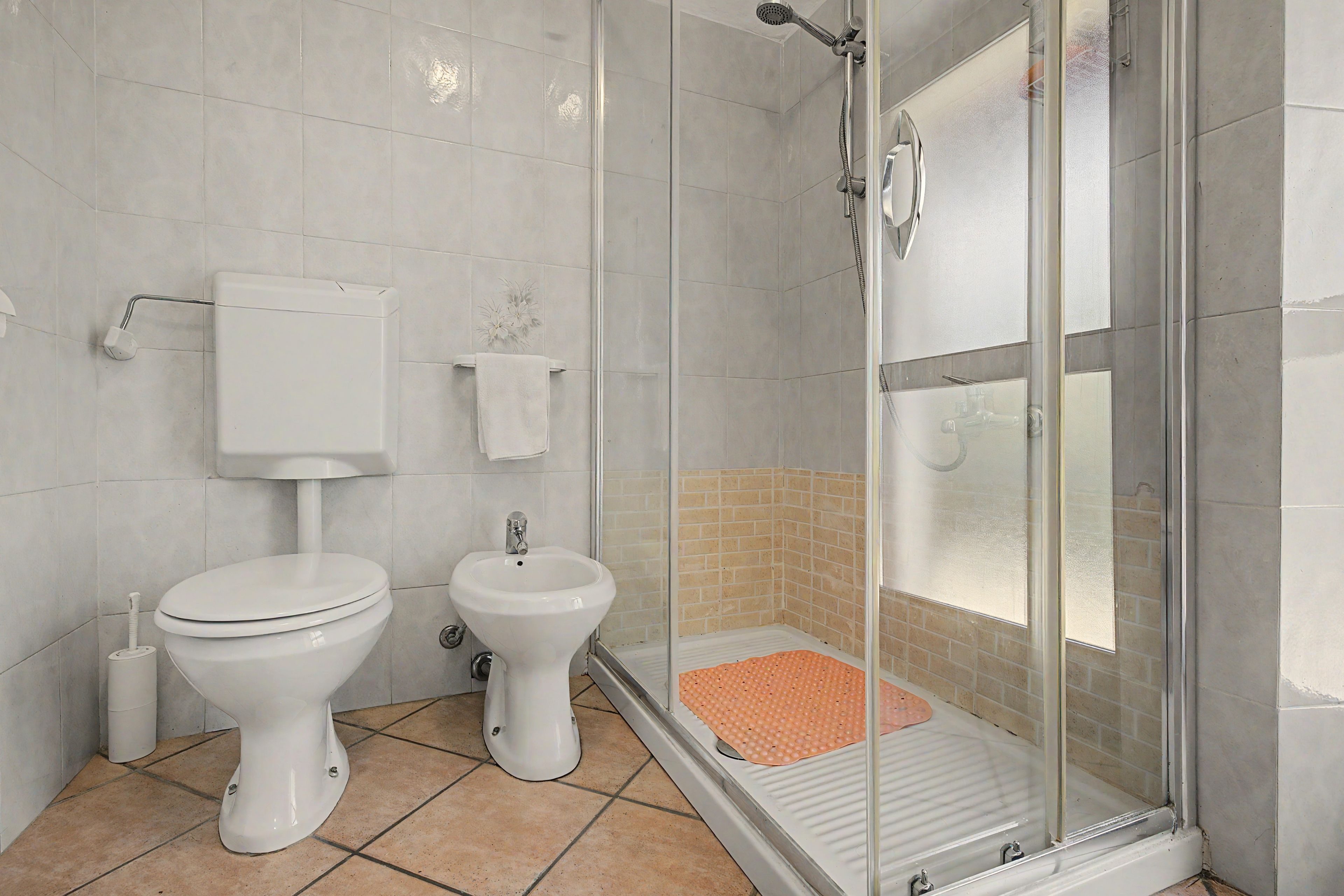 A bathroom with a toilet, bidet, and a glass-enclosed shower area.