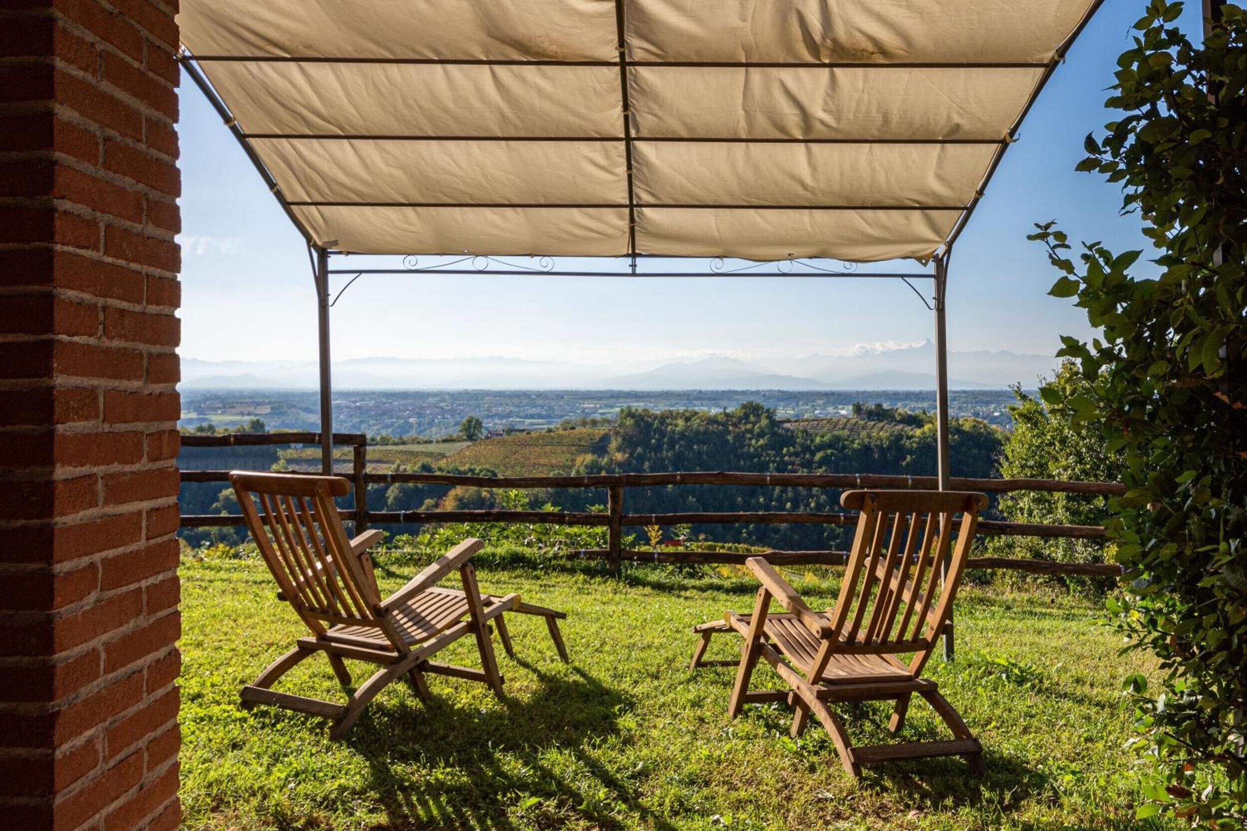 Un espace extérieur abrité, aménagé avec deux chaises en bois et une table, offrant une vue sur un paysage pittoresque.