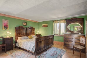 A bedroom with a large bed, a dresser, a chair, and a mirror.