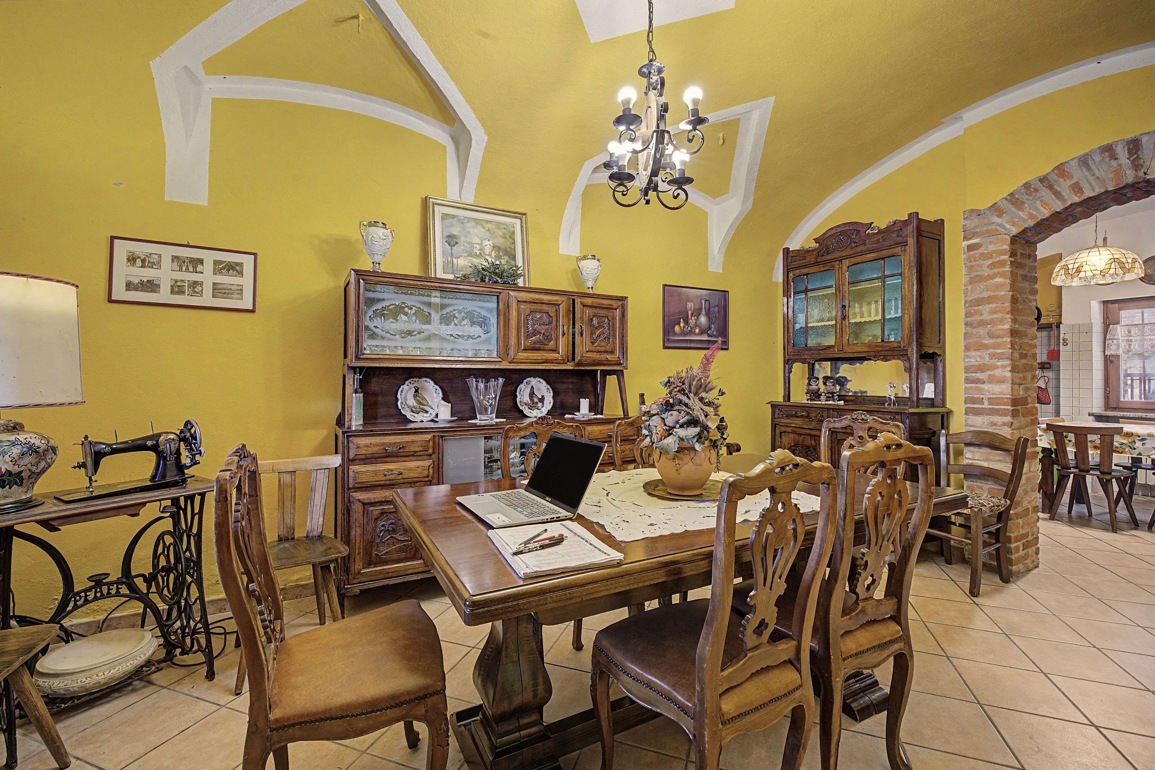 A dining area with a wooden table, chairs, a chandelier, and various decorative items on the walls.