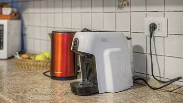 A kitchen with a coffee maker, a red kettle, and a microwave.