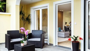 A modern outdoor seating area with wicker furniture and potted plants. - Cozy One-Bedroom Retreat with Private Patio & Sunrise Views in Madeira (Ponta do Sol)