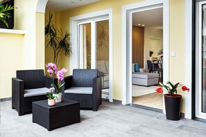 A modern outdoor seating area with wicker furniture and potted plants. - Cozy One-Bedroom Retreat with Private Patio & Sunrise Views in Madeira (Ponta do Sol)
