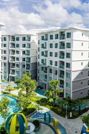 Ein mehrstöckiges Hotel mit Balkonen, einem Swimmingpool und einem Spielbereich für Kinder.