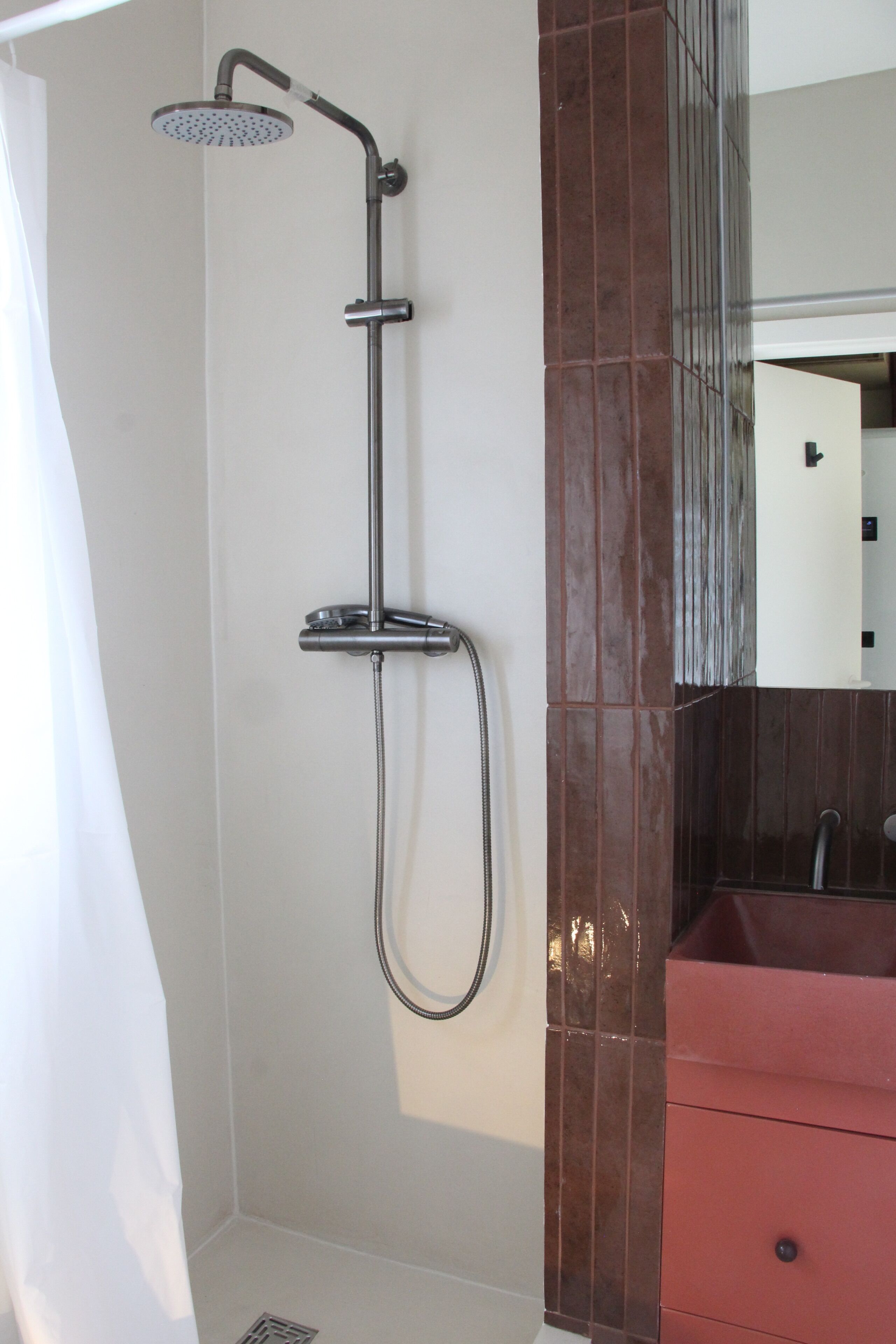 A shower with a handheld showerhead and a wall-mounted faucet.
