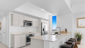 Una cocina moderna con una isla central, electrodomésticos de acero inoxidable y un amplio ventanal que aporta luz natural.