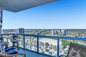 A balcony with wicker chairs and a view of a cityscape including buildings and a river. - Penthouse Retreat Pool Beach Access (Hallandale Beach)