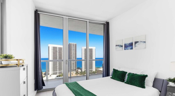 Ein modernes Schlafzimmer mit einer großen Schiebetür zu einem Balkon mit Blick auf die Stadt.