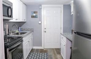 A compact kitchen with white cabinets, a stainless steel refrigerator, a microwave, and a stove. - Private Midtown Atl Apartment -  5 minutes from Mercedes Benz Stadium (Atlanta)