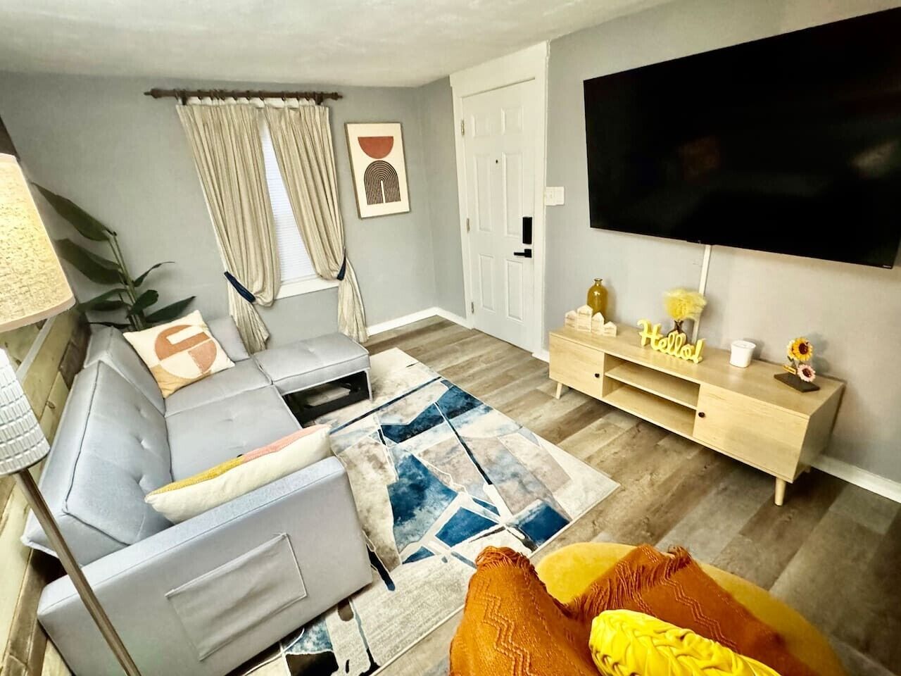 A living room with a sofa, a coffee table, a TV, a wooden cabinet, and a door.
