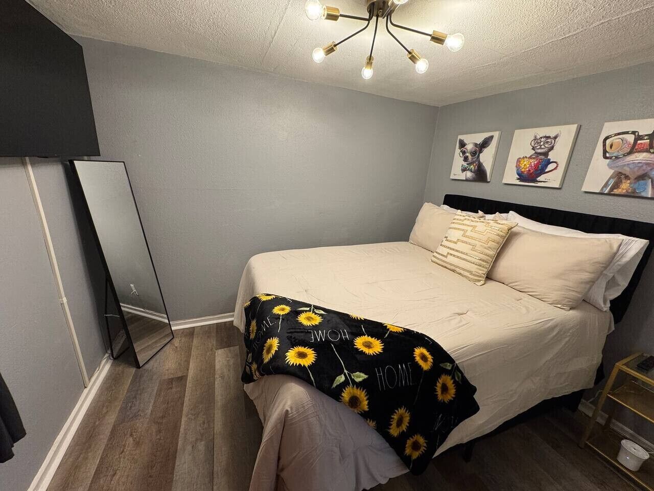 Ein Schlafzimmer mit einem Bett, einem Nachttisch, einem Spiegel und Wandbildern.