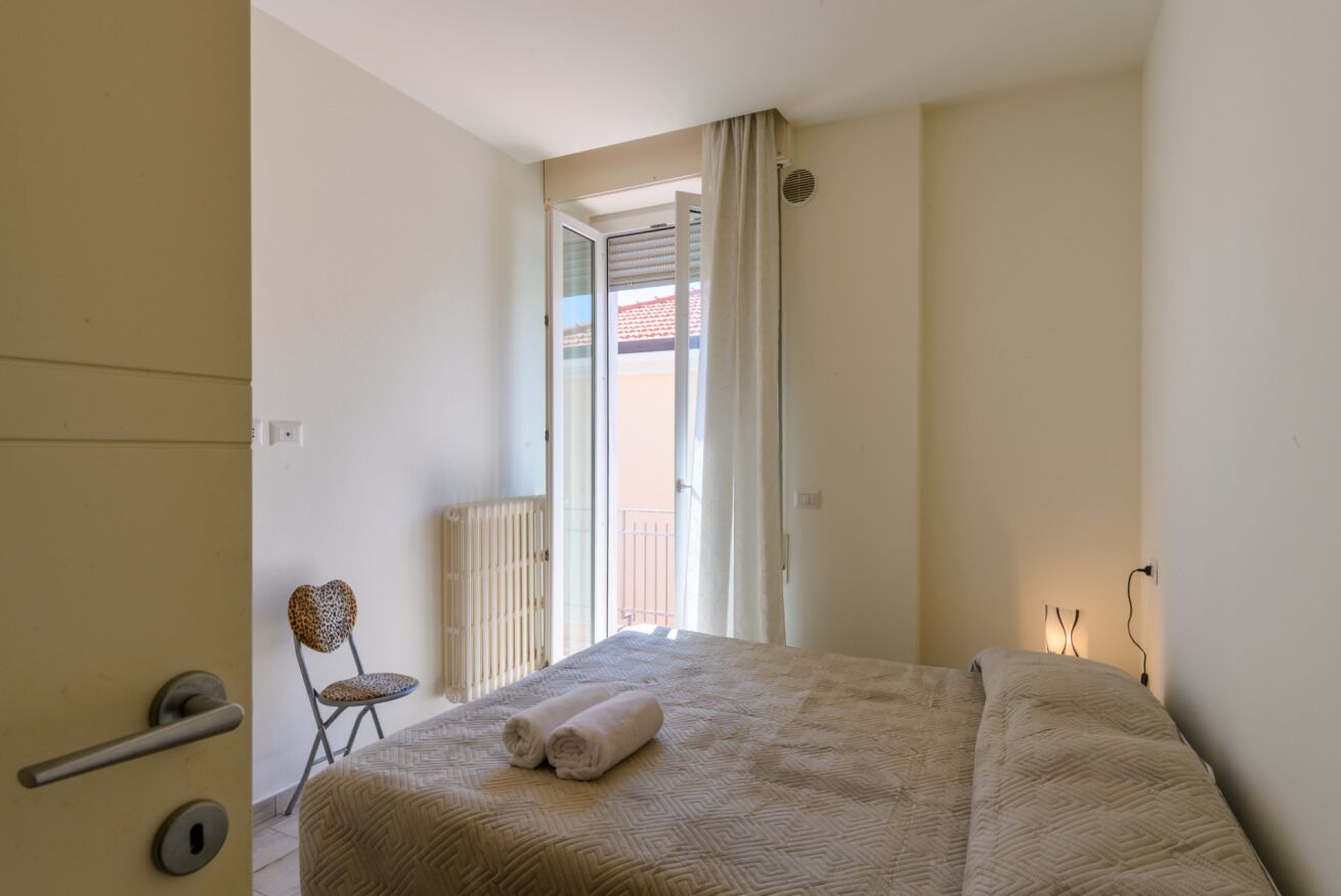 Un dormitorio con cama, una silla y vistas al exterior.