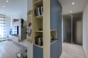 A modern living room with a built-in bookshelf, a flat-screen TV, and a sliding door closet. - GuestHost - Flaminia 36 Apartment (Pesaro)