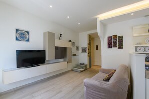 A modern living room with a flat-screen TV, built-in shelving, a sofa, and artwork on the walls. - GuestHost - Flaminia 36 Apartment (Pesaro)