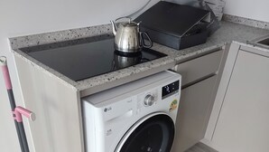 A compact kitchen with a washing machine, a kettle, and a mop. - Cozy 2-bedroom apartment at BTS  pho nimit with AC icon Siam (Krung Thep Maha Nakhon)