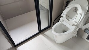 A bathroom with a white toilet, a glass shower enclosure, and tiled flooring. - Cozy 2-bedroom apartment at BTS  pho nimit with AC icon Siam (Krung Thep Maha Nakhon)