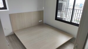 A room with a wooden floor, a white wall, and a window with a view of buildings. - Cozy 2-bedroom apartment at BTS  pho nimit with AC icon Siam (Krung Thep Maha Nakhon)