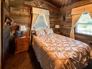 A wooden cabin bedroom with a bed, nightstands, and a window with curtains. - *NEW* River Valley Retreat ~ directly on White River (Mountain View)