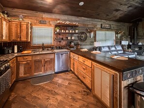 A rustic kitchen with wooden cabinets, a built-in dishwasher, and a stone countertop. - *NEW* River Valley Retreat ~ directly on White River (Mountain View)