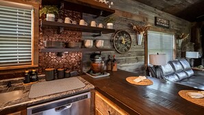 A kitchen with a stainless steel dishwasher, a wooden countertop, and a bar area with a leather couch. - *NEW* River Valley Retreat ~ directly on White River (Mountain View)