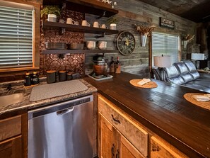 A kitchen with a stainless steel dishwasher, a wooden countertop, and a bar area with a leather couch. - *NEW* River Valley Retreat ~ directly on White River (Mountain View)