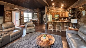 A spacious living room with leather sofas, a wooden coffee table, and a kitchen area with a bar. - *NEW* River Valley Retreat ~ directly on White River (Mountain View)