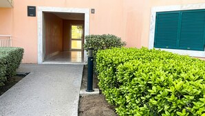 A building entrance with a paved walkway, a hedge, and a door leading to an interior space. - Chic Studio with Pool - Vila Verde (1 to 4 people) (Santa Maria)