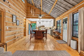 Ein Holzblockhaus mit Essbereich, Küche und großen Fenstern.