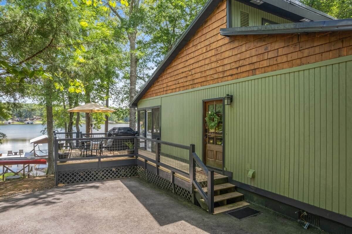 Une cabane dotée d’une terrasse donnant sur un lac, avec un espace salon extérieur et un escalier.