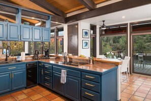 A kitchen with blue cabinets, a large island, and a view of the outdoors. - Palisades Villa | 360 Views, Hot Tub, Mid-Century (Sedona)