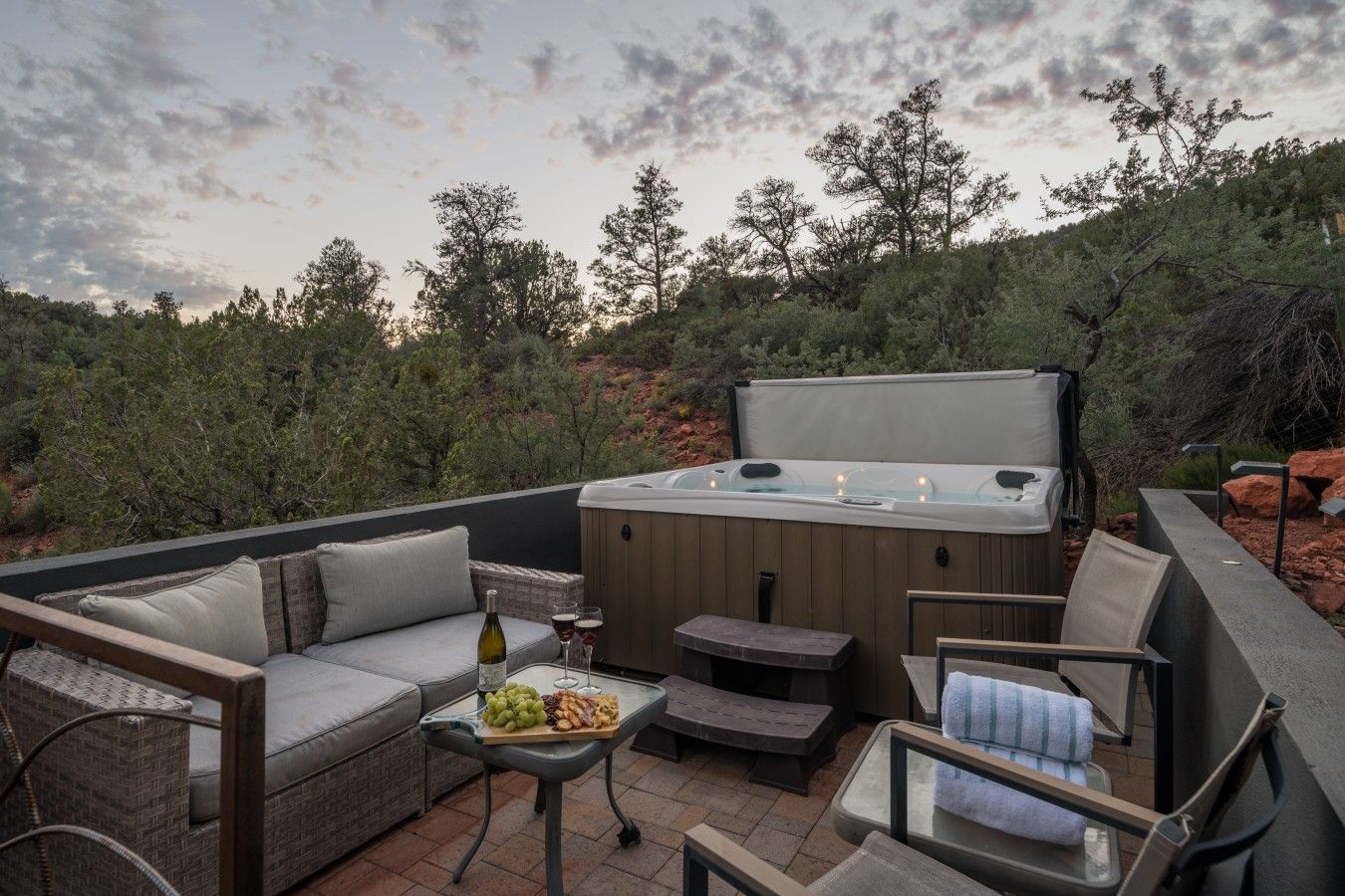 Une terrasse extérieure dotée d’un jacuzzi, d’un coin salon et d’une table où sont servis des collations et des boissons.