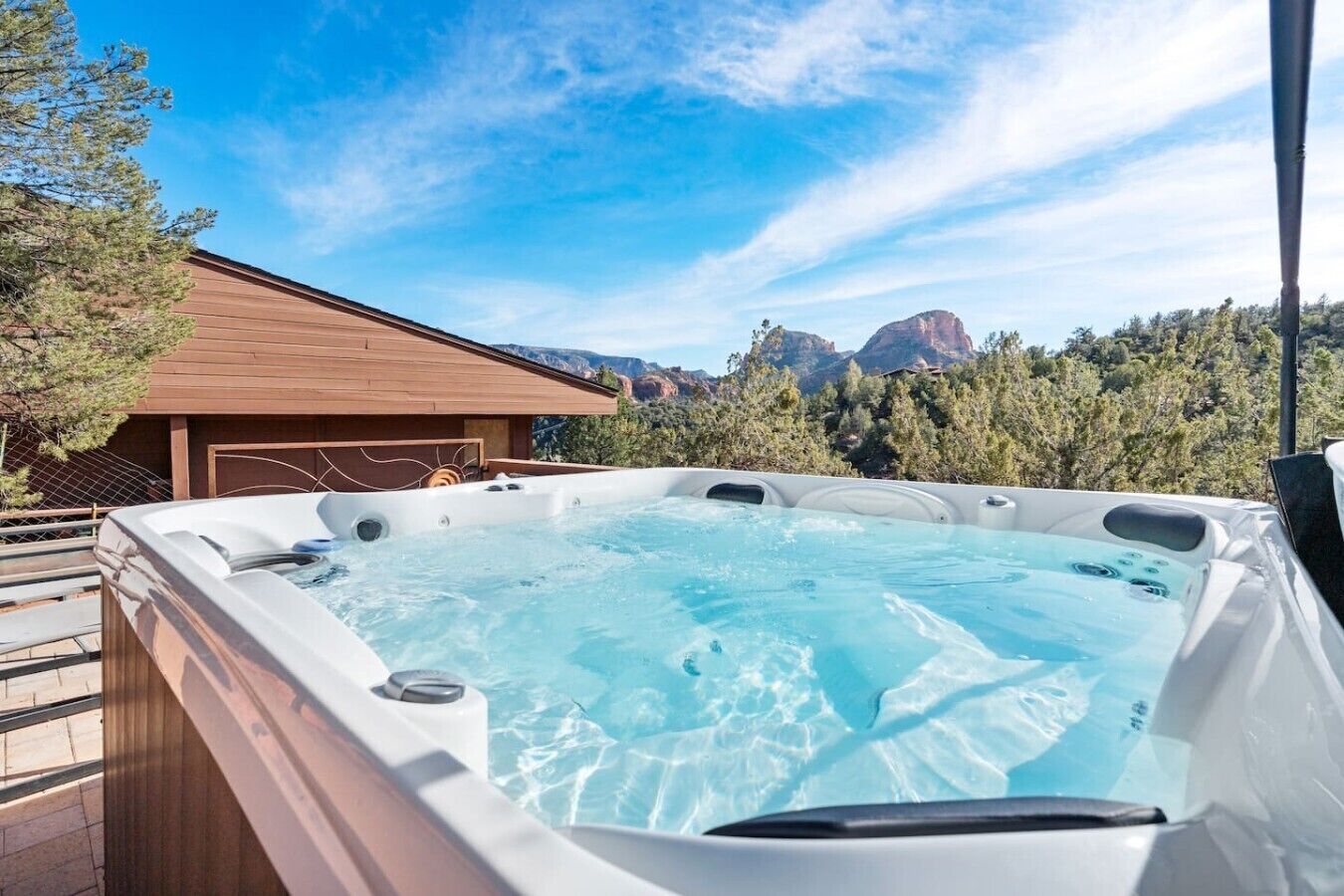 Un bain à remous avec une terrasse en bois et une vue sur les montagnes.
