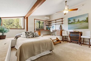 Ein Schlafzimmer mit einem Bett, Schreibtisch, Stühlen und einem Gemälde.