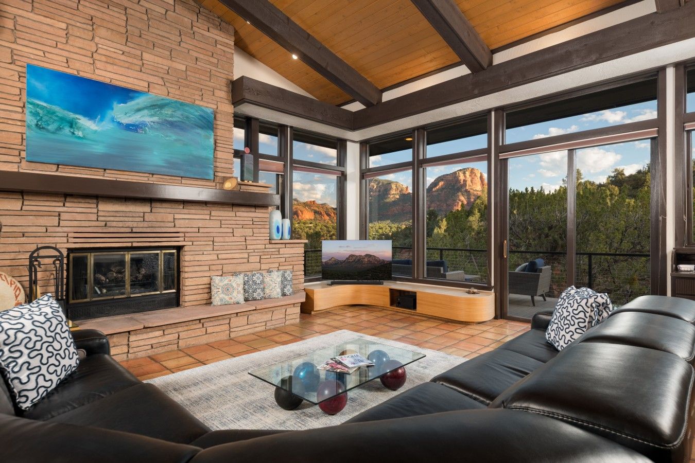 A modern living room with a fireplace, large windows, and a view of mountains.