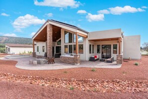 Ein modernes Haus mit steinernen Säulen, einer überdachten Terrasse und einem Pool.
